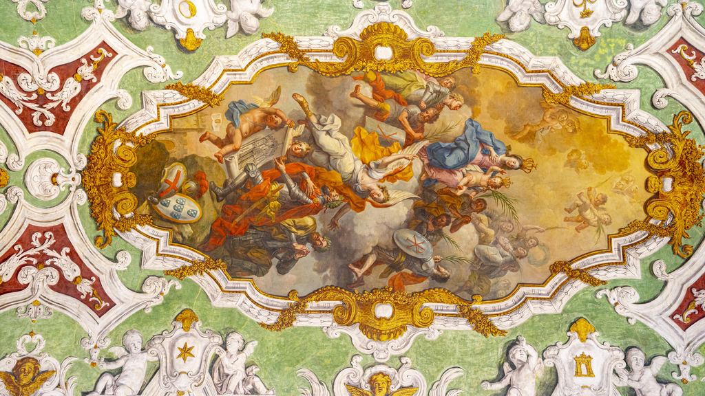 A baroque painted vault with figures on clouds inside white stucco frames