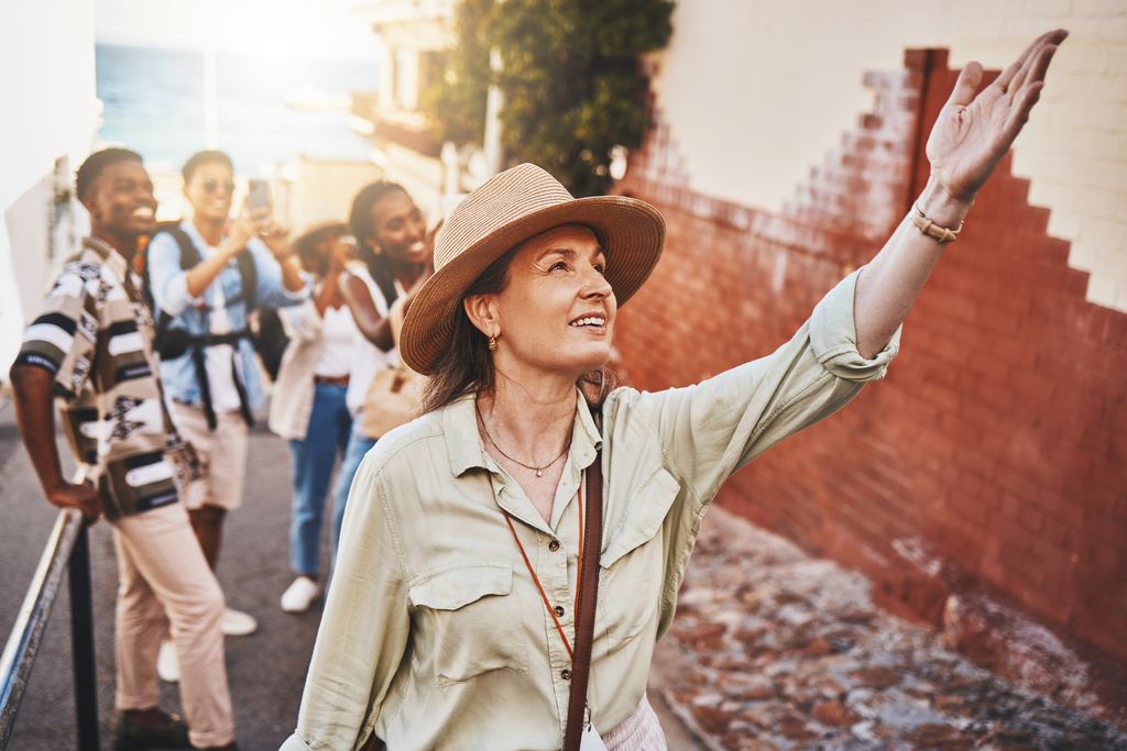 A guide raising an arm to point out a detail of old brickwork while a small group looks up