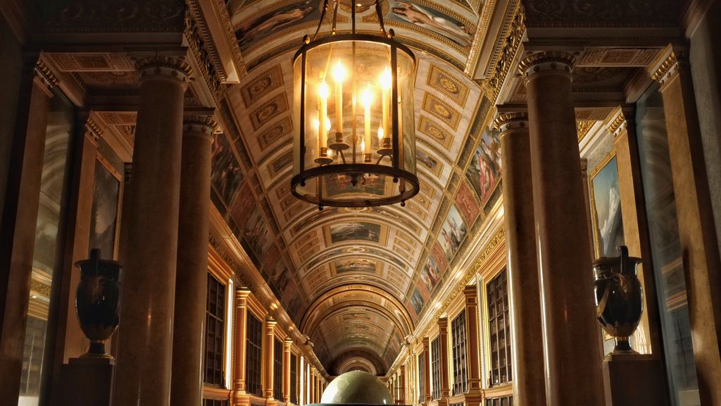 A long vaulted corridor with marble columns and a hanging lantern in warm low light
