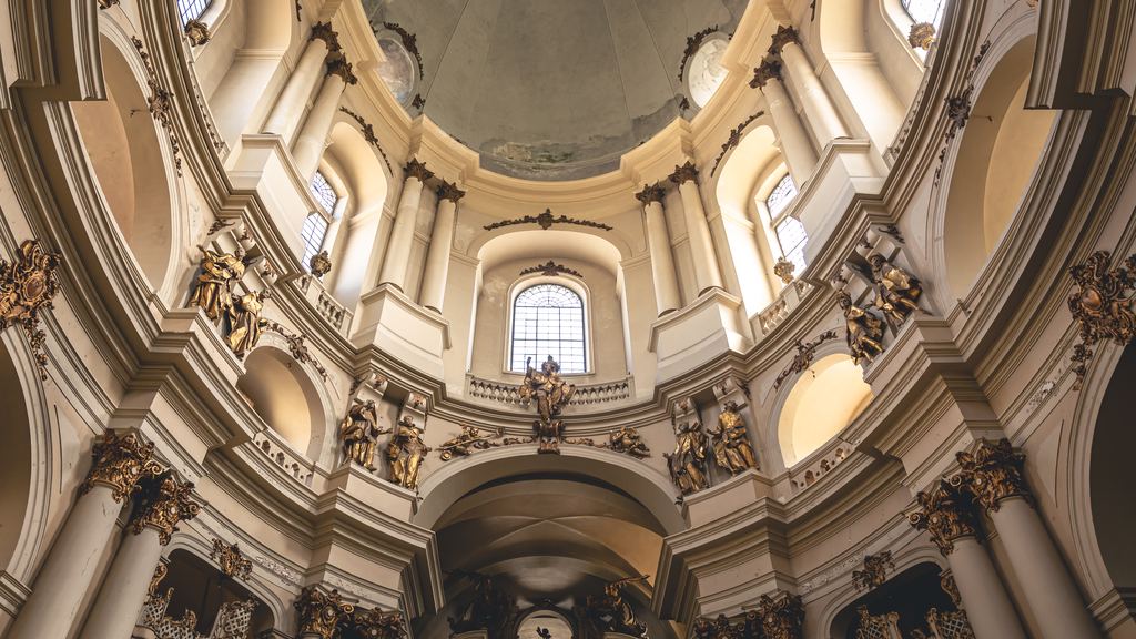 The interior of a baroque room with gilded ribs, stucco and statues in niches