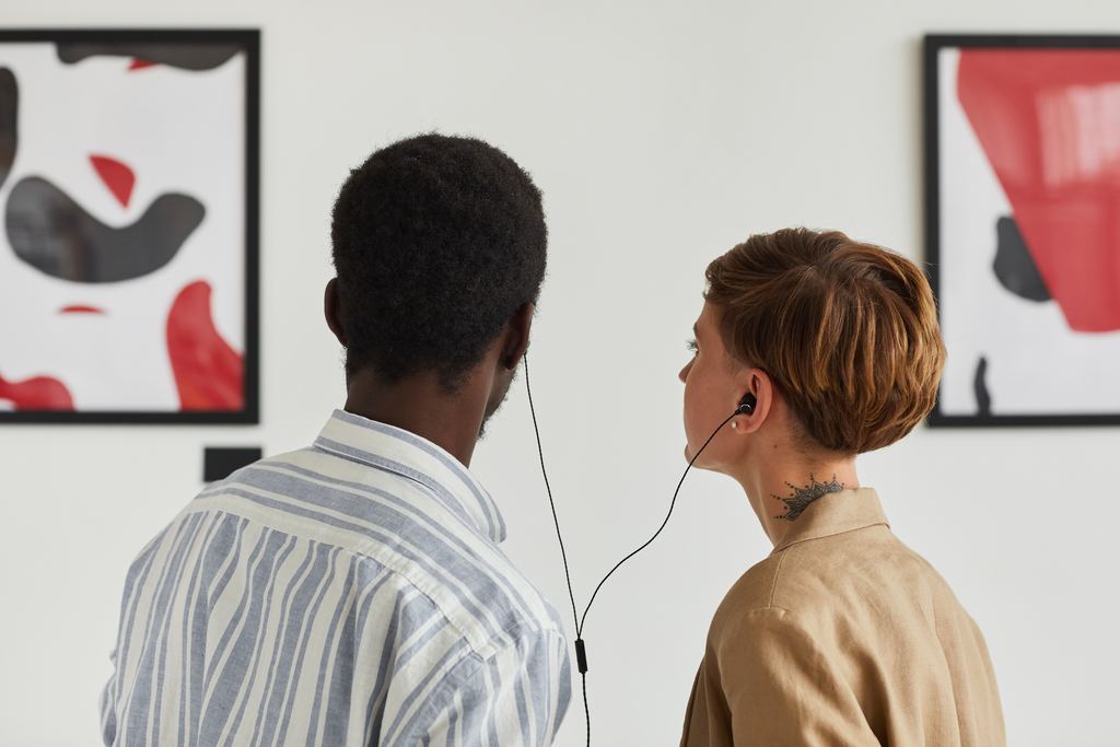 Two visitors from behind sharing a wired audio guide between them