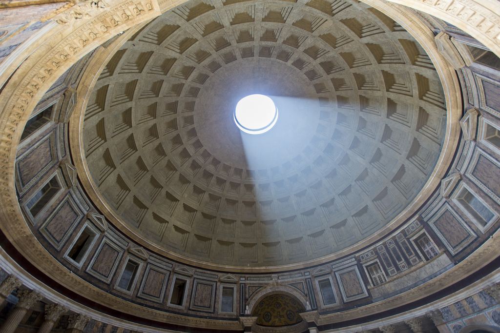 A shaft of sunlight falls through the oculus of the Pantheon in Rome onto the coffered concrete dome