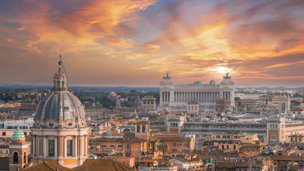 A panorama over Rome's roofs and domes under orange evening cloud