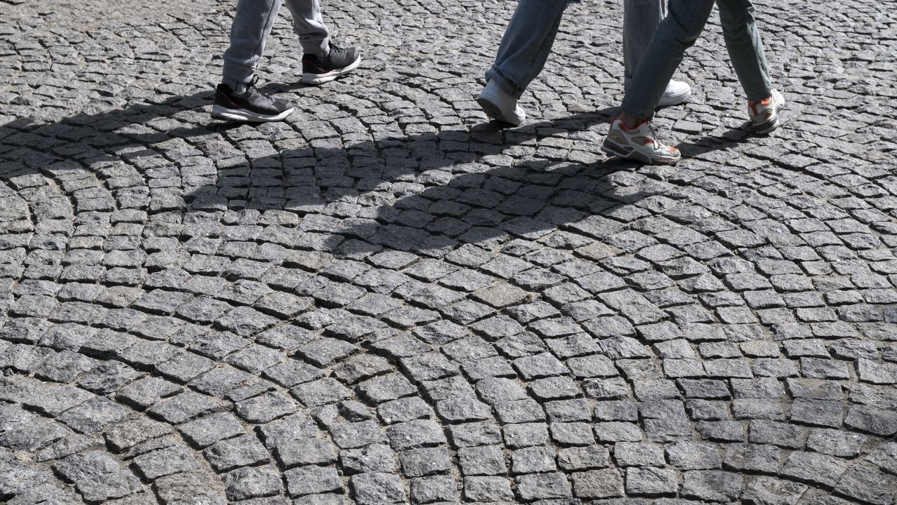 Close view of Rome's basalt sampietrini paving with two people walking across it in trainers