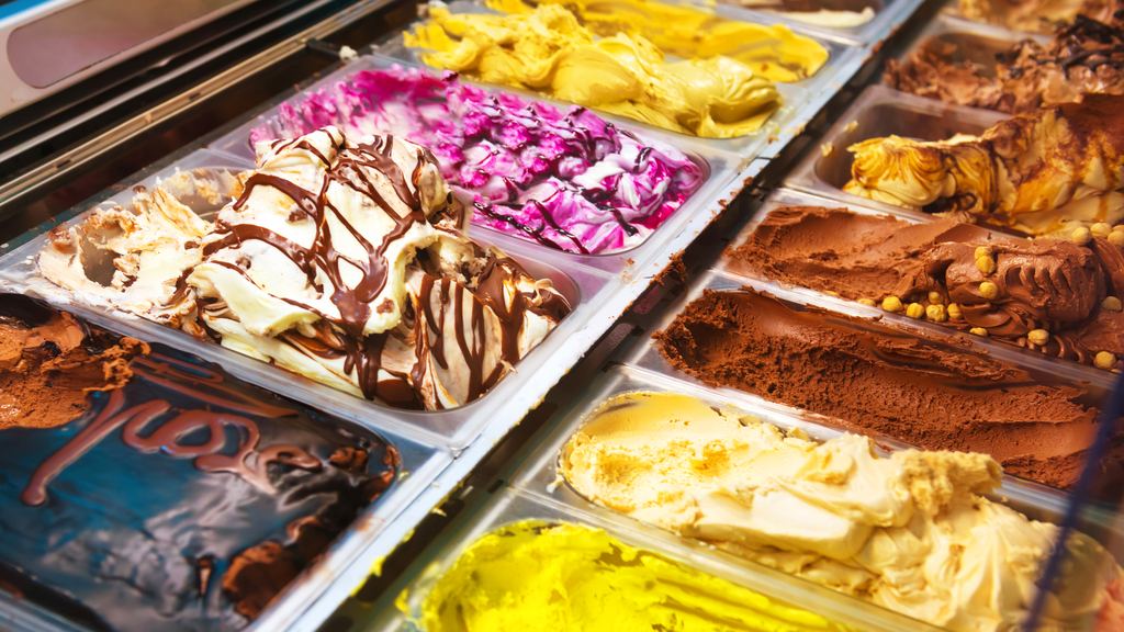 Metal tubs of gelato behind curved glass, worked into ridges