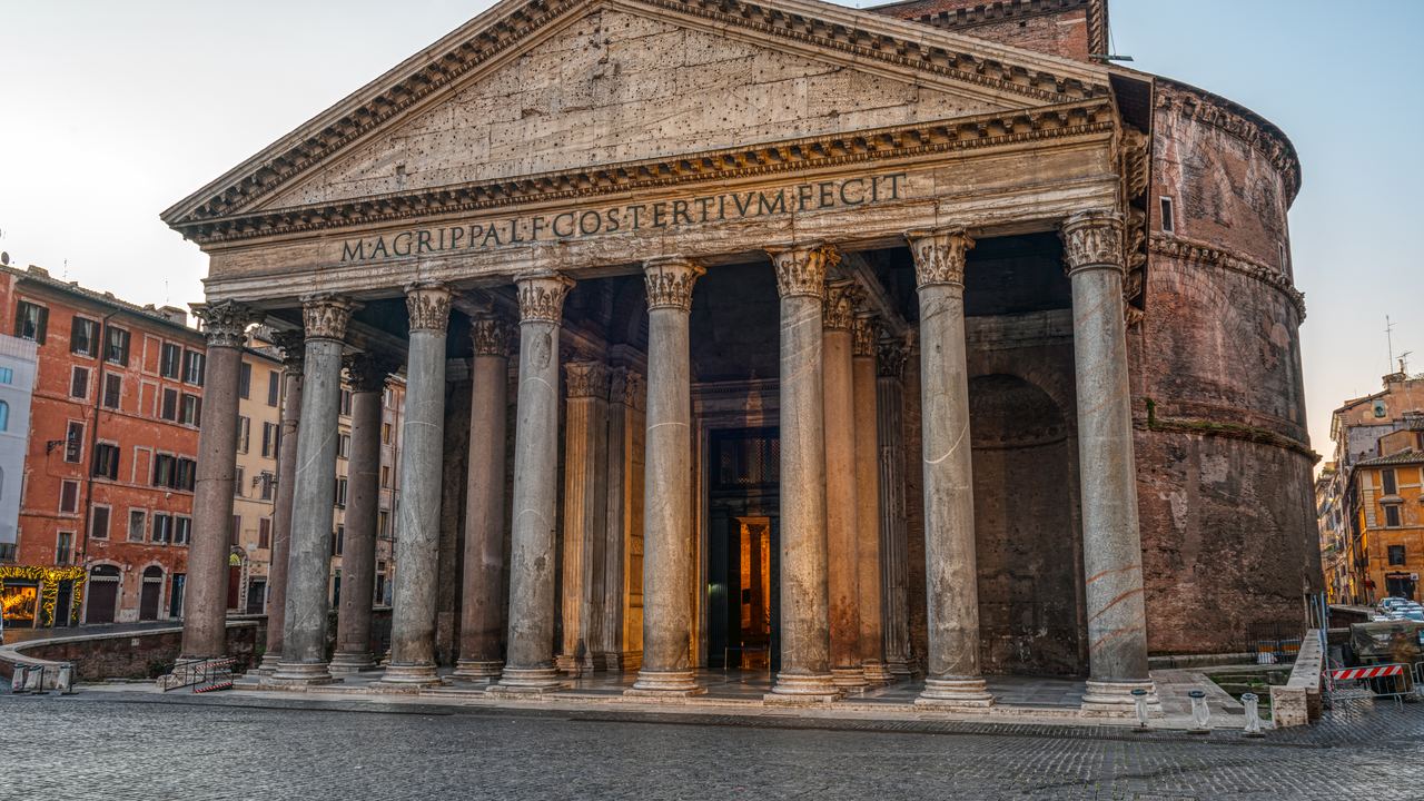 The front of the Pantheon in Rome in early morning light, the cobbled square in front of it completely empty