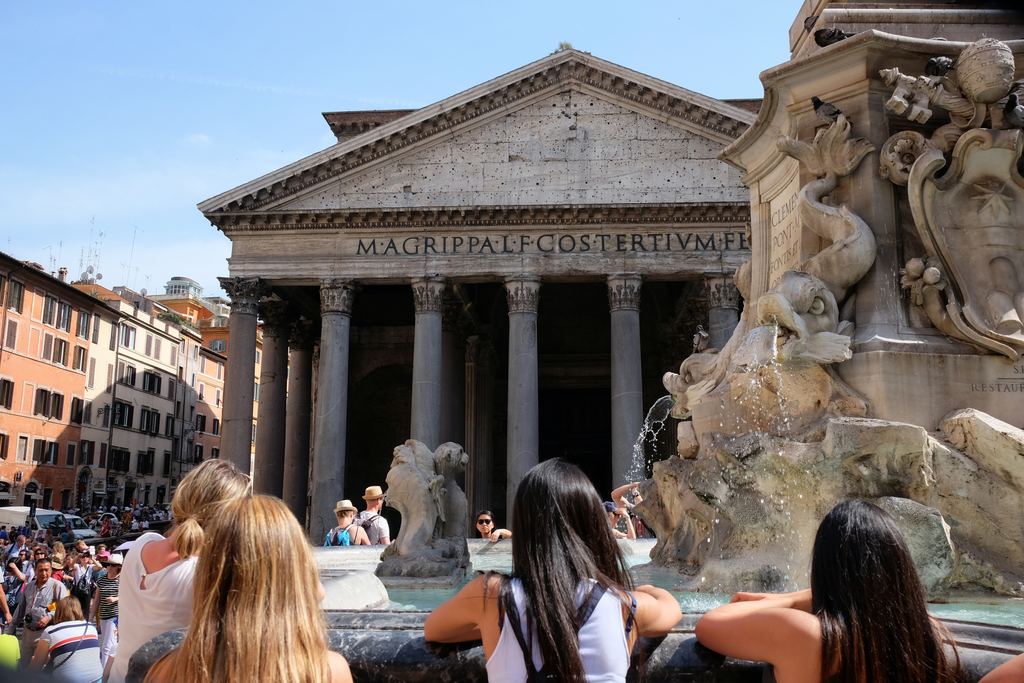 People sitting on the fountain rim and queuing in Piazza della Rotonda, the Pantheon's inscription behind them