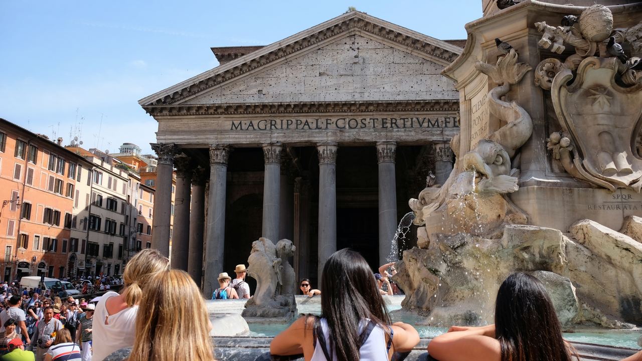 People sitting on the fountain rim and queuing in Piazza della Rotonda, the Pantheon's inscription behind them